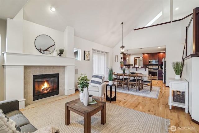 living room with a fireplace, recessed lighting, light wood-style floors, and high vaulted ceiling