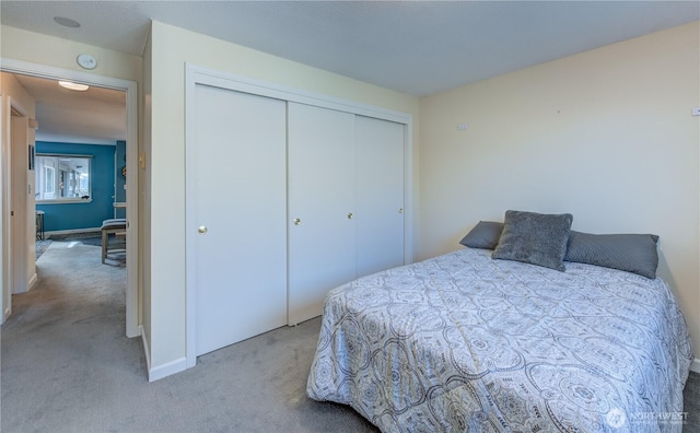 bedroom featuring baseboards, a closet, and light colored carpet