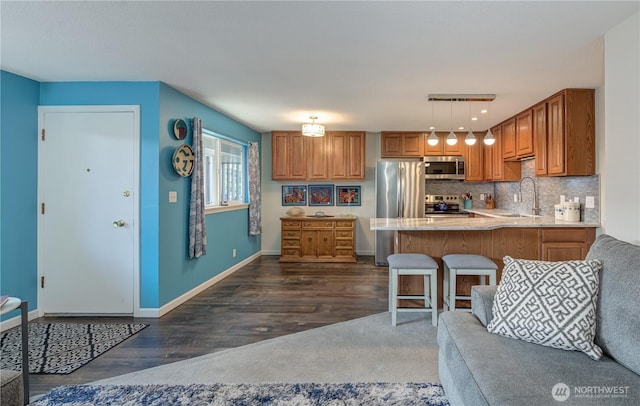 kitchen featuring appliances with stainless steel finishes, a peninsula, hanging light fixtures, light countertops, and a sink