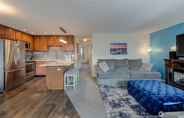 kitchen with pendant lighting, stainless steel appliances, open floor plan, a sink, and a kitchen bar