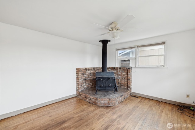 interior details featuring cooling unit, hardwood / wood-style floors, ceiling fan, and a wood stove