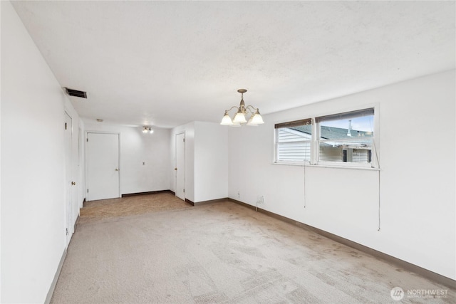 empty room with a notable chandelier and light colored carpet