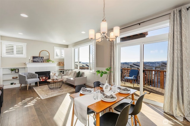 dining space featuring an inviting chandelier, wood-type flooring, and a tile fireplace