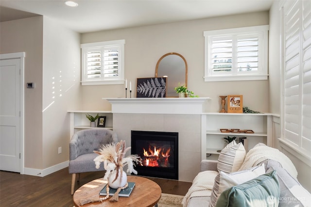 living room with a tiled fireplace and dark hardwood / wood-style flooring