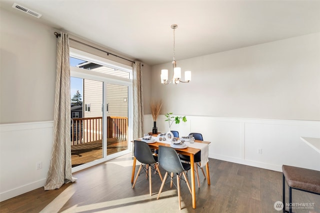 dining area featuring dark hardwood / wood-style floors and an inviting chandelier