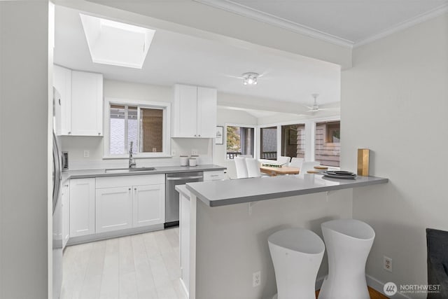 kitchen with sink, stainless steel dishwasher, a kitchen breakfast bar, kitchen peninsula, and white cabinets