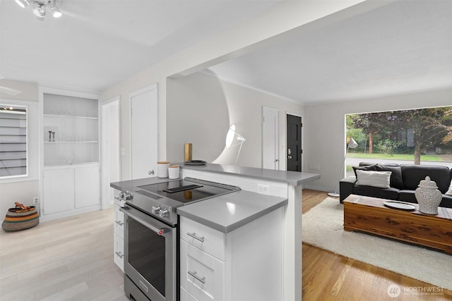 kitchen with white cabinetry, a center island, high end stainless steel range, and light hardwood / wood-style flooring