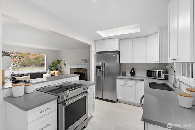 kitchen featuring white cabinetry, appliances with stainless steel finishes, light hardwood / wood-style floors, and sink