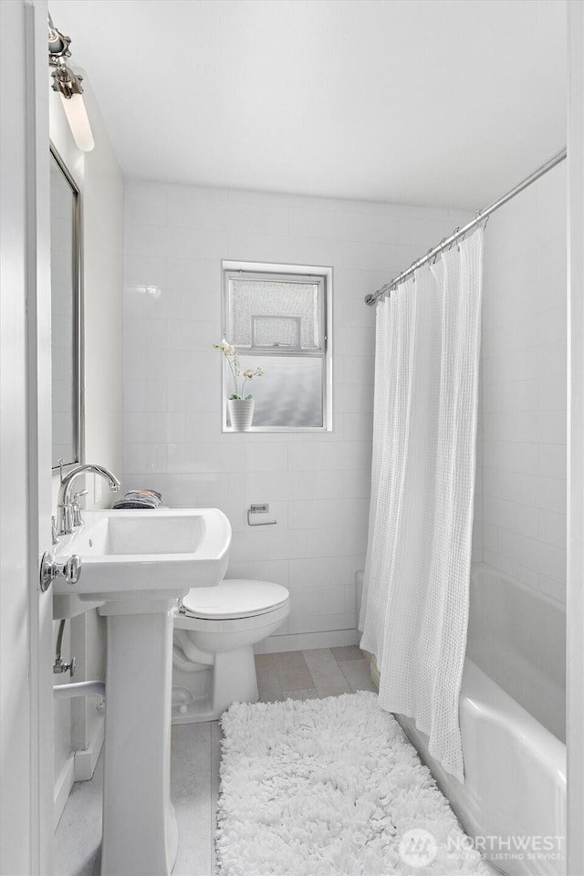 bathroom with tile patterned flooring, tile walls, shower / bath combination with curtain, and toilet