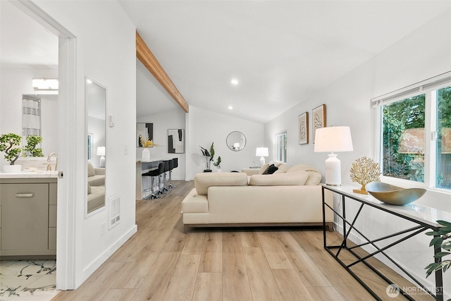 living room featuring light wood-type flooring and vaulted ceiling with beams