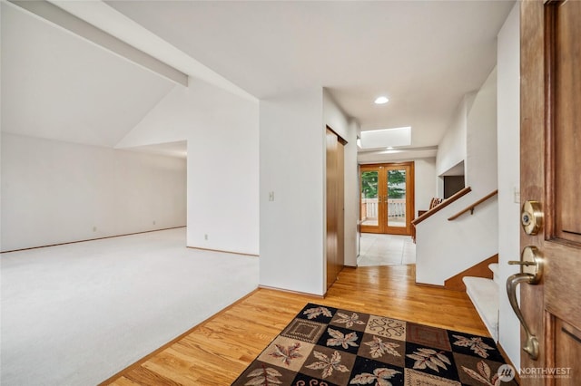 entryway featuring french doors, vaulted ceiling, stairway, and wood finished floors