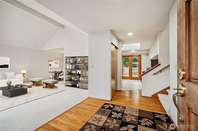 entryway with vaulted ceiling with beams, french doors, stairway, and wood finished floors