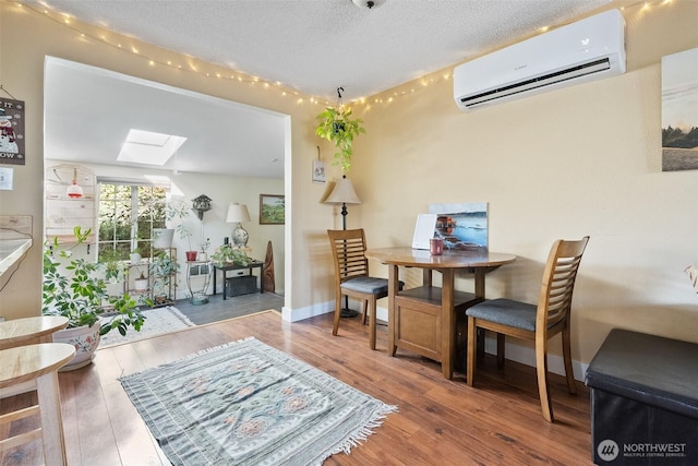 sitting room featuring hardwood / wood-style flooring, a wall mounted AC, a textured ceiling, and a skylight