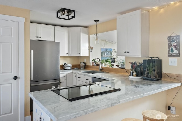 kitchen featuring sink, a breakfast bar area, white cabinetry, kitchen peninsula, and light stone countertops