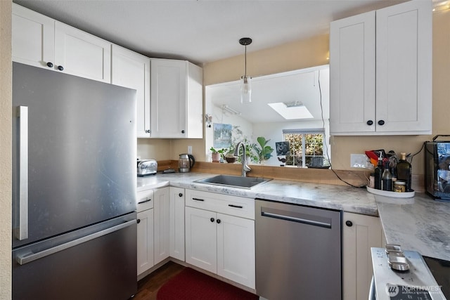 kitchen with sink, hanging light fixtures, a skylight, stainless steel appliances, and white cabinets