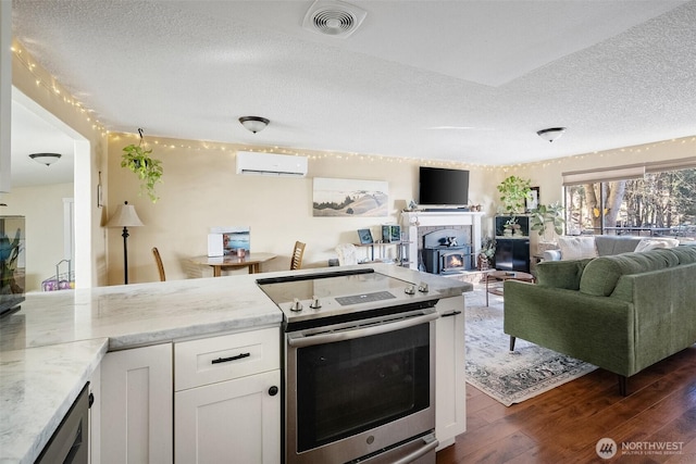 kitchen with electric range, a wall unit AC, light stone countertops, white cabinets, and dark hardwood / wood-style flooring