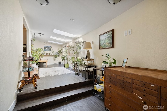 corridor with dark hardwood / wood-style flooring and vaulted ceiling with skylight