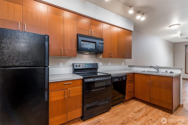 kitchen featuring light wood finished floors, light countertops, a sink, a peninsula, and black appliances