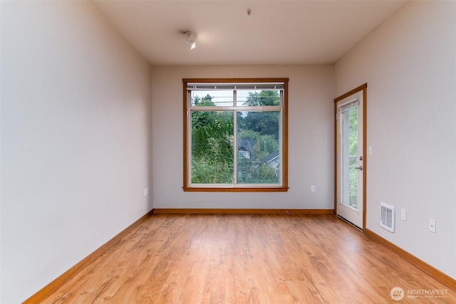 spare room with baseboards, visible vents, and light wood-style floors