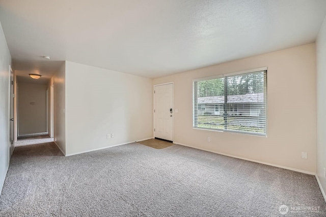 empty room with a textured ceiling, carpet floors, and baseboards