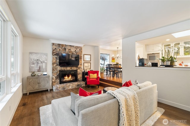 living room featuring dark wood-type flooring, a fireplace, and a notable chandelier