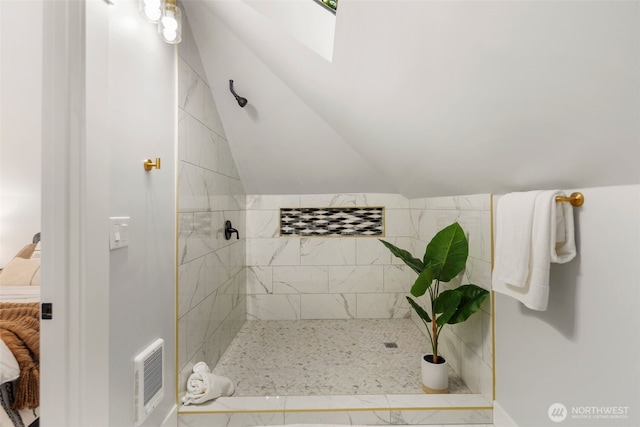 bathroom with tiled shower and lofted ceiling with skylight