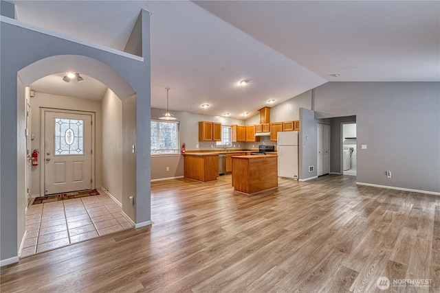 kitchen featuring open floor plan, hanging light fixtures, light countertops, a center island, and stainless steel appliances