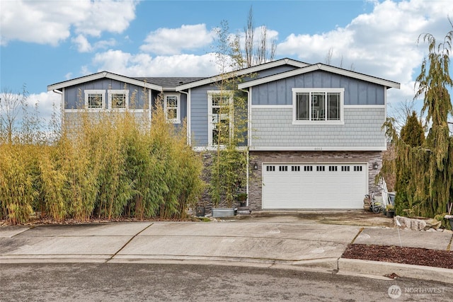 view of front of home with an attached garage, stone siding, board and batten siding, and concrete driveway