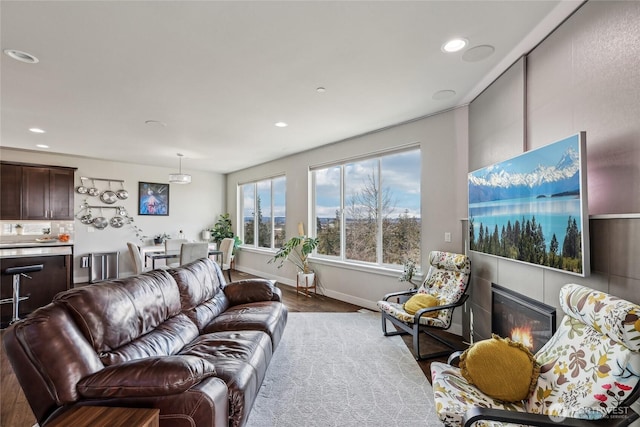 living area featuring recessed lighting, baseboards, and a glass covered fireplace