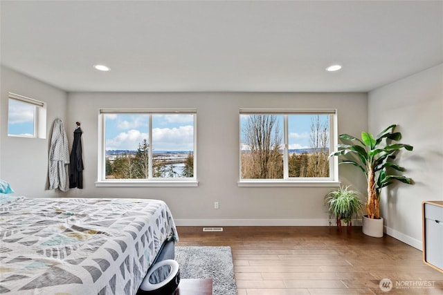 bedroom featuring multiple windows, visible vents, and dark wood-style flooring