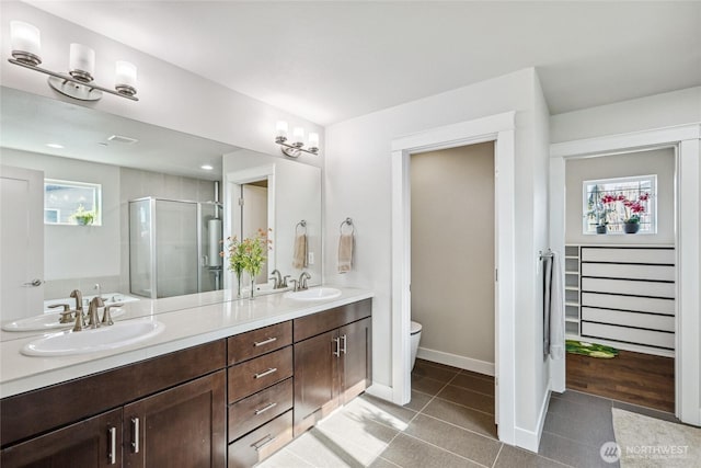 full bath featuring double vanity, tile patterned flooring, a shower stall, and a sink