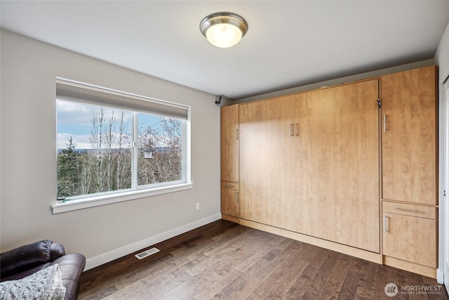 unfurnished bedroom featuring dark wood-type flooring, visible vents, and baseboards