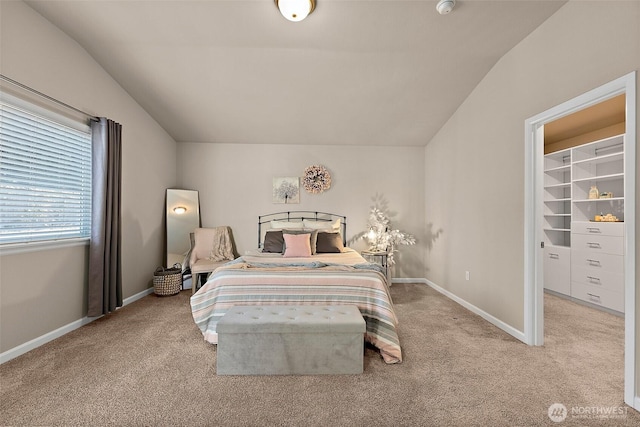 bedroom featuring lofted ceiling, a walk in closet, and light carpet