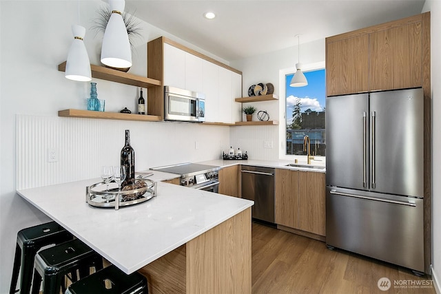 kitchen featuring a kitchen bar, sink, decorative light fixtures, appliances with stainless steel finishes, and kitchen peninsula