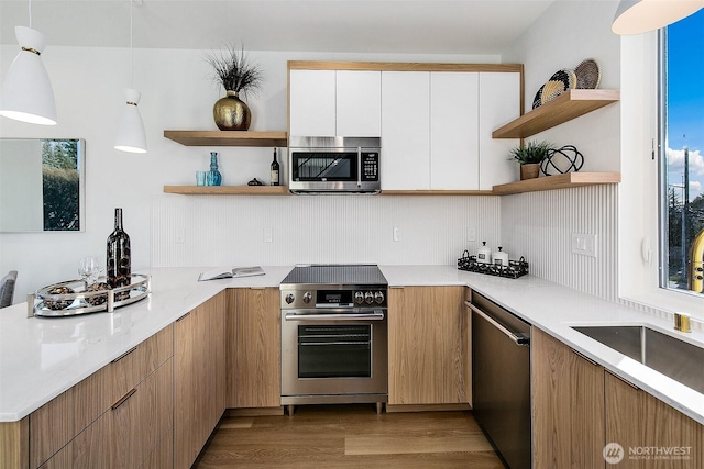 kitchen featuring decorative light fixtures, light hardwood / wood-style flooring, stainless steel appliances, and white cabinets