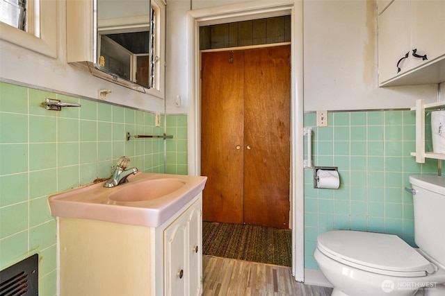 bathroom featuring hardwood / wood-style flooring, vanity, tile walls, and toilet