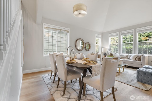 dining area featuring lofted ceiling, light wood-type flooring, and a healthy amount of sunlight