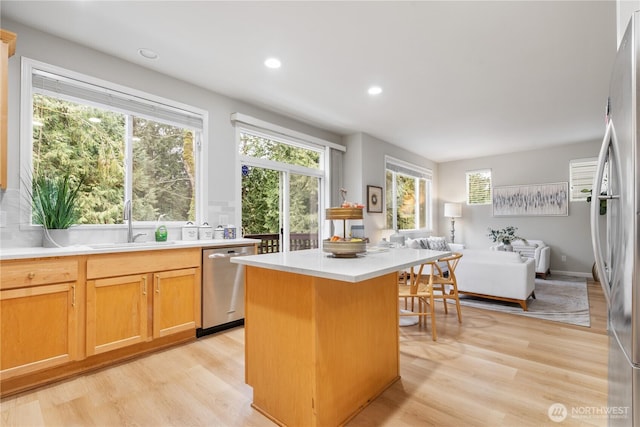 kitchen featuring sink, light wood-type flooring, stainless steel appliances, and a center island