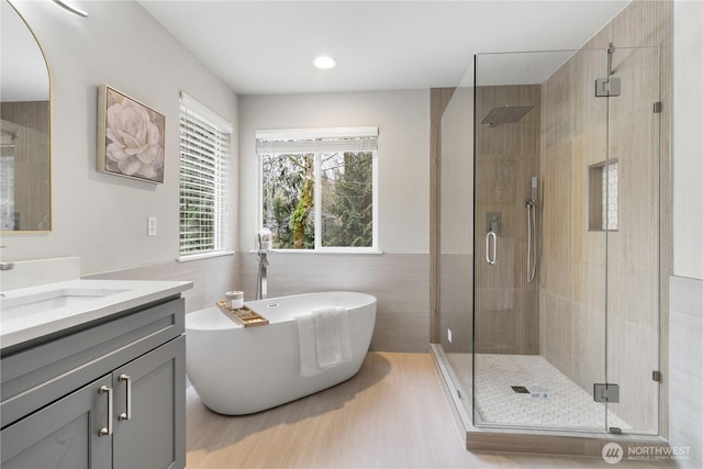 bathroom featuring tile walls, vanity, independent shower and bath, and wood-type flooring