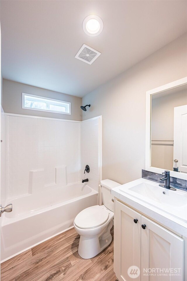 full bathroom featuring visible vents, toilet, wood finished floors, vanity, and shower / bathing tub combination