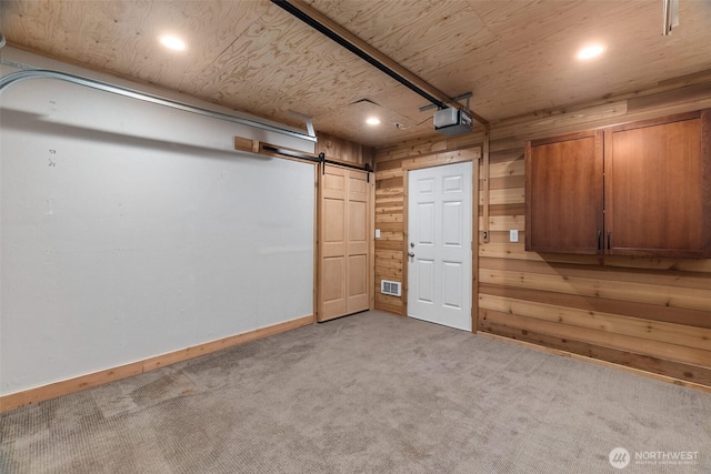 interior space with recessed lighting, a barn door, light colored carpet, and wood walls