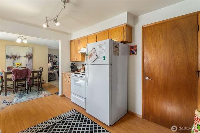 kitchen with track lighting, under cabinet range hood, light countertops, light wood-style flooring, and white appliances