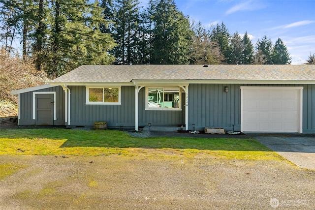 ranch-style home with board and batten siding, an attached garage, driveway, and a front yard