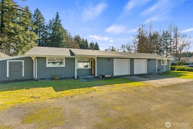 ranch-style house with board and batten siding, a front lawn, a garage, and driveway