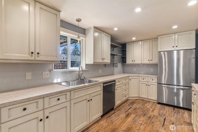 kitchen featuring open shelves, a sink, stainless steel appliances, light countertops, and light wood-style floors