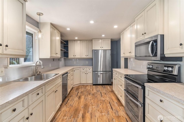 kitchen with open shelves, stainless steel appliances, light countertops, and a sink