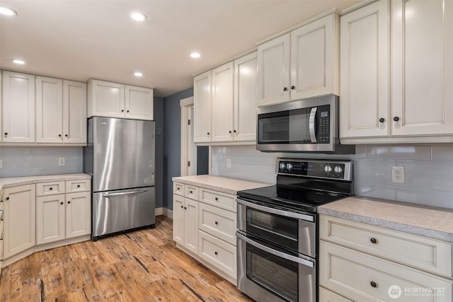 kitchen featuring light wood-type flooring, stainless steel appliances, backsplash, and light countertops