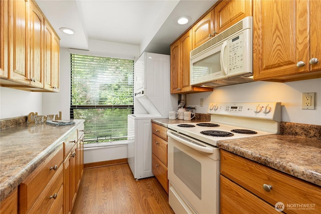 3710 25th Pl W Unit 401, Seattle, WA 98199 - kitchen with white appliances, estacked washer and dryer, light wood-style floors, recessed lighting, and brown cabinetry