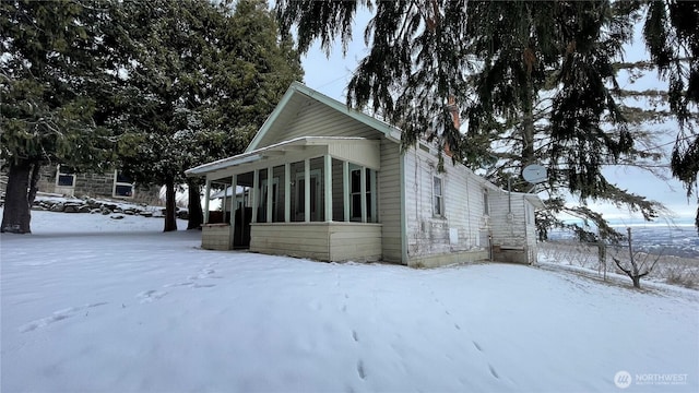 view of snow covered exterior with a sunroom