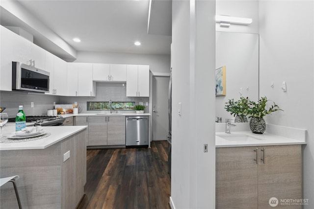 kitchen with white cabinetry, sink, stainless steel appliances, and dark hardwood / wood-style floors